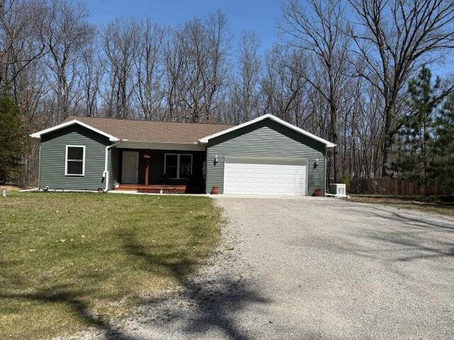 ranch-style house featuring a porch, driveway, a front yard, a garage, and fence