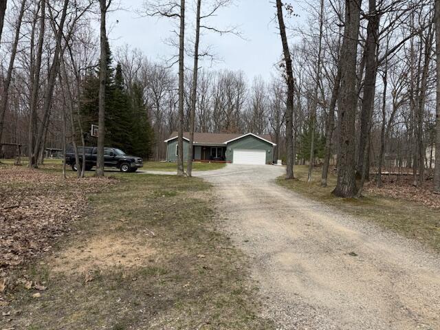 view of front of home featuring a garage and dirt driveway
