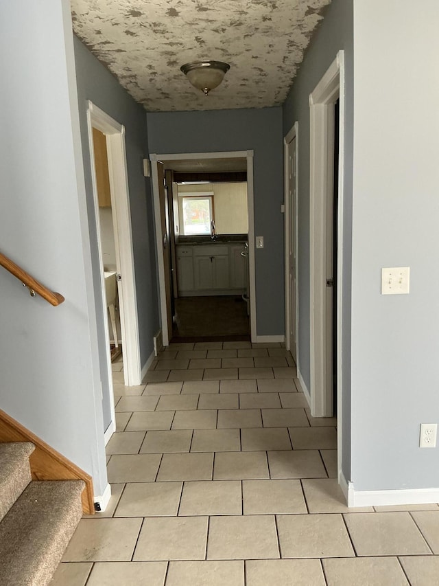 120 Marina St, Houghton Lake, MI 48629 - hall with light tile patterned flooring, baseboards, and stairway
