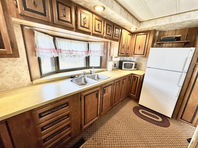 427 Goline Rd, Grayling, MI 49738 - kitchen featuring brown cabinetry, a sink, light countertops, freestanding refrigerator, and carpet flooring
