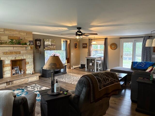 living area with a baseboard radiator, ceiling fan, and wood finished floors
