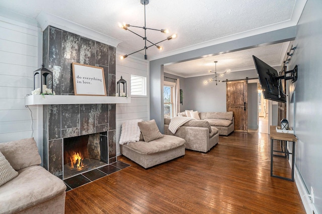 334 E Main St, Gaylord, MI 49735 - living room featuring a barn door, crown molding, a textured ceiling, wood-type flooring, and a chandelier