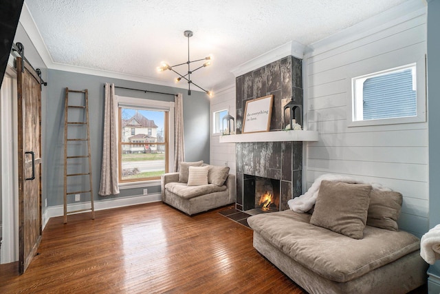 334 E Main St, Gaylord, MI 49735 - sitting room featuring a barn door, a tile fireplace, a chandelier, wood finished floors, and a textured ceiling