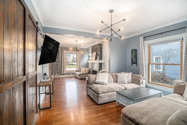334 E Main St, Gaylord, MI 49735 - living room featuring ornamental molding, dark wood-style flooring, a barn door, a chandelier, and a textured ceiling
