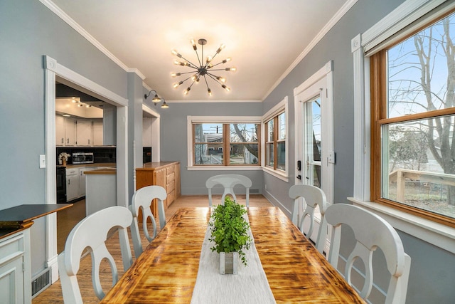 334 E Main St, Gaylord, MI 49735 - dining room with a chandelier, crown molding, baseboards, and light wood-style floors