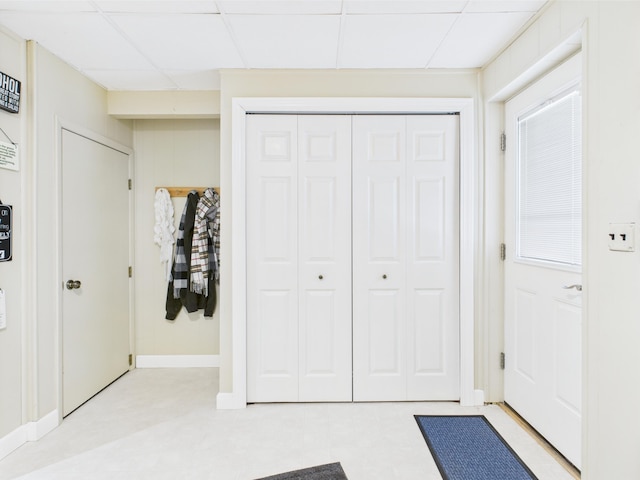 unfurnished bedroom with light floors, baseboards, a closet, and a drop ceiling
