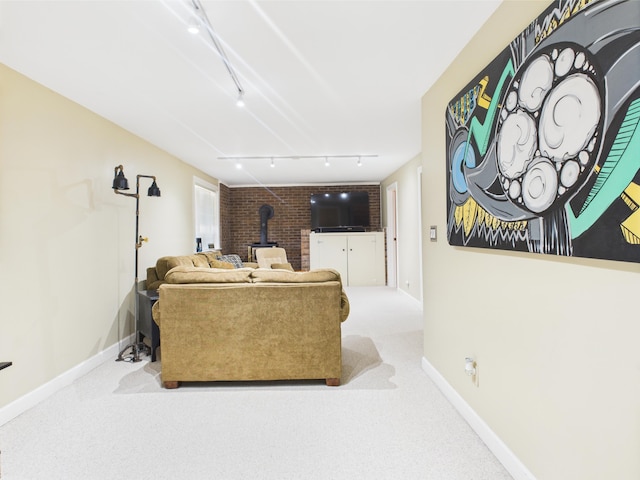 carpeted living area with baseboards, a wood stove, and rail lighting