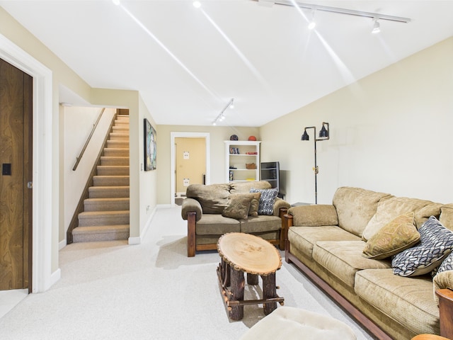 carpeted living area featuring baseboards, lofted ceiling, track lighting, and stairway