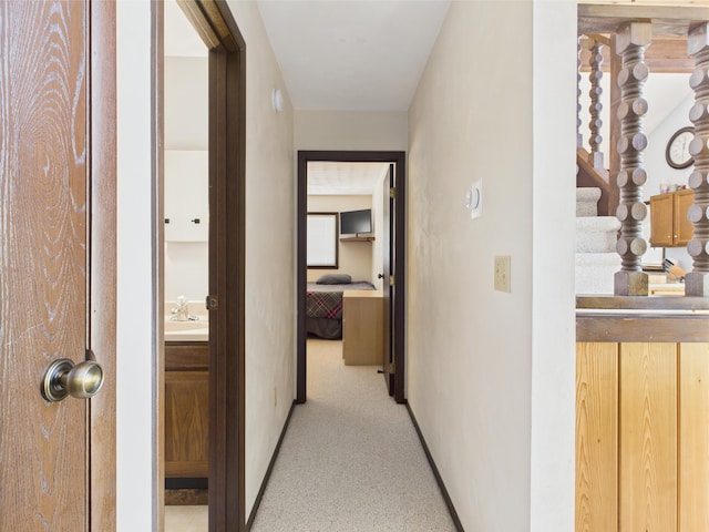 hall featuring baseboards, light colored carpet, and stairway