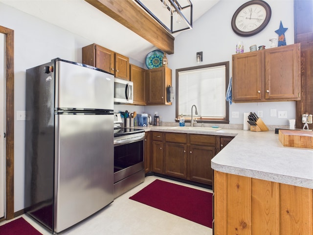 kitchen with a sink, light countertops, light floors, vaulted ceiling with beams, and stainless steel appliances