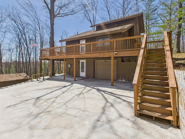 back of house with stairway, a wooden deck, and a garage