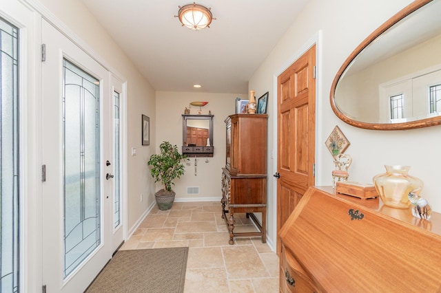 entryway with visible vents, stone tile floors, baseboards, and recessed lighting