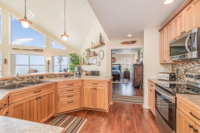 kitchen with decorative backsplash, light brown cabinetry, light countertops, a sink, and stainless steel appliances
