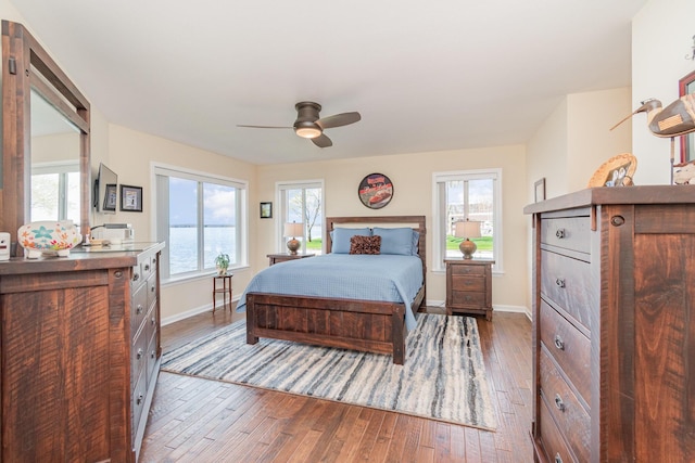 bedroom with baseboards, multiple windows, ceiling fan, and hardwood / wood-style flooring