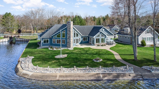 rear view of house featuring a yard, a water view, and a chimney