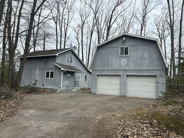 view of front of home featuring a gambrel roof, an outbuilding, and a detached garage