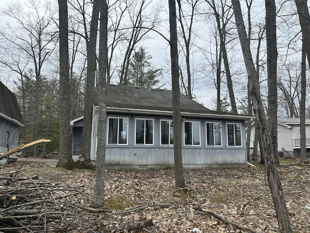 view of side of home featuring crawl space and a shingled roof