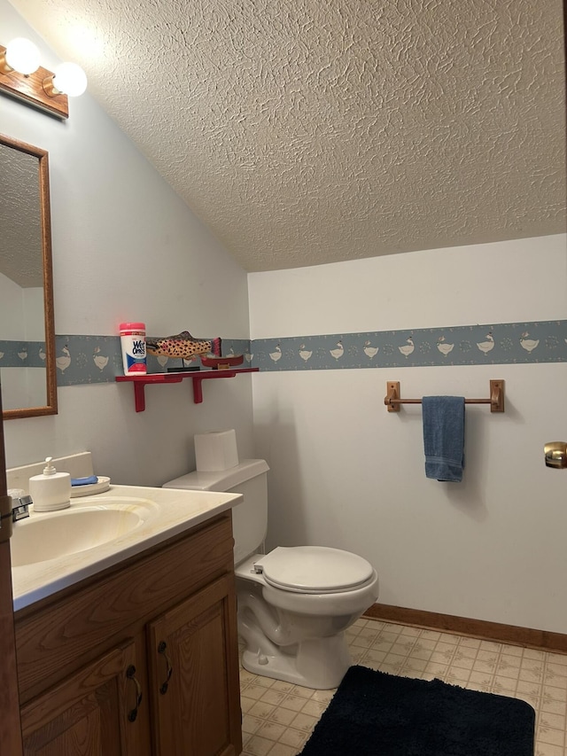 half bath with vanity, a textured ceiling, lofted ceiling, and toilet