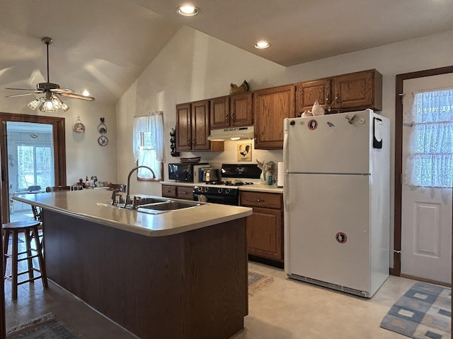 kitchen with ceiling fan, gas stove, a sink, freestanding refrigerator, and under cabinet range hood