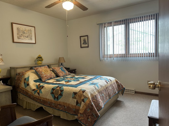 carpeted bedroom with baseboards, a ceiling fan, and visible vents