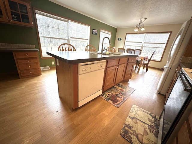 kitchen featuring dishwasher, a sink, a notable chandelier, ornamental molding, and light wood-style flooring