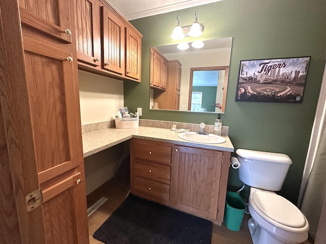 bathroom with crown molding, vanity, toilet, and visible vents