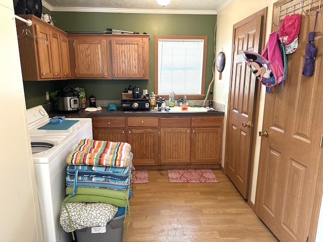 laundry room with crown molding, light wood-style flooring, cabinet space, and independent washer and dryer