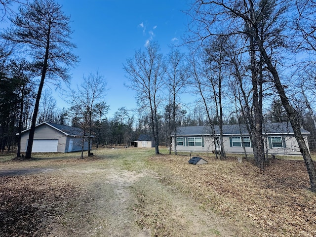 exterior space with a detached garage, an outbuilding, and dirt driveway