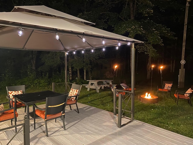 3047 Timberlane Trl, Grayling, MI 49738 - patio at night with a fire pit, a wooden deck, a gazebo, a yard, and outdoor dining space