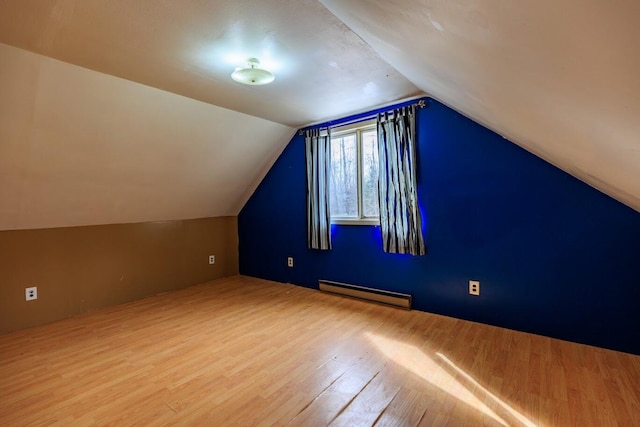 additional living space with a baseboard heating unit, wood finished floors, and vaulted ceiling