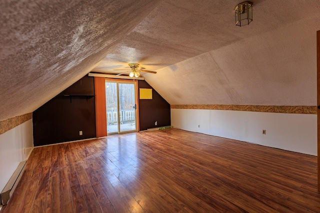 bonus room featuring a textured ceiling, vaulted ceiling, baseboard heating, and hardwood / wood-style flooring