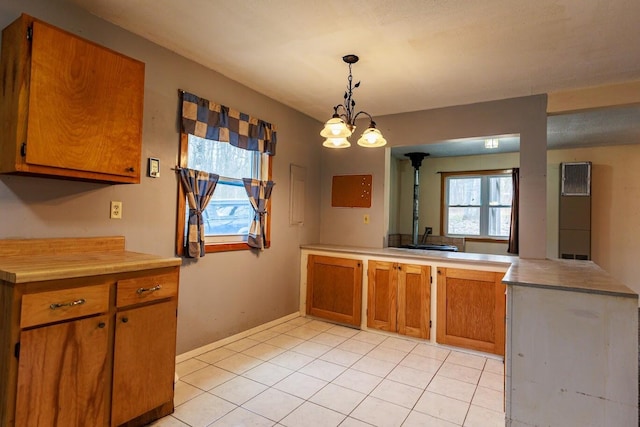 kitchen featuring brown cabinetry, pendant lighting, light countertops, a peninsula, and light tile patterned flooring