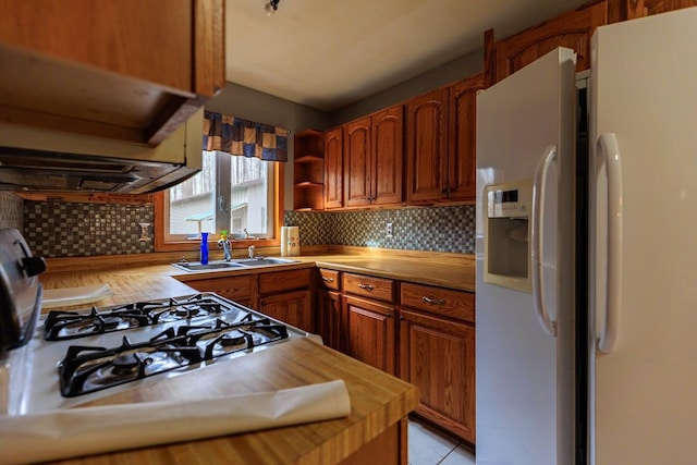 kitchen featuring open shelves, a sink, white fridge with ice dispenser, and tasteful backsplash