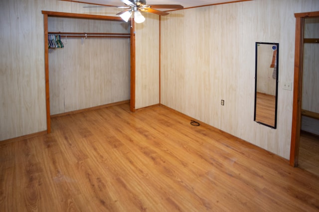 unfurnished bedroom featuring a ceiling fan, wood walls, and wood finished floors