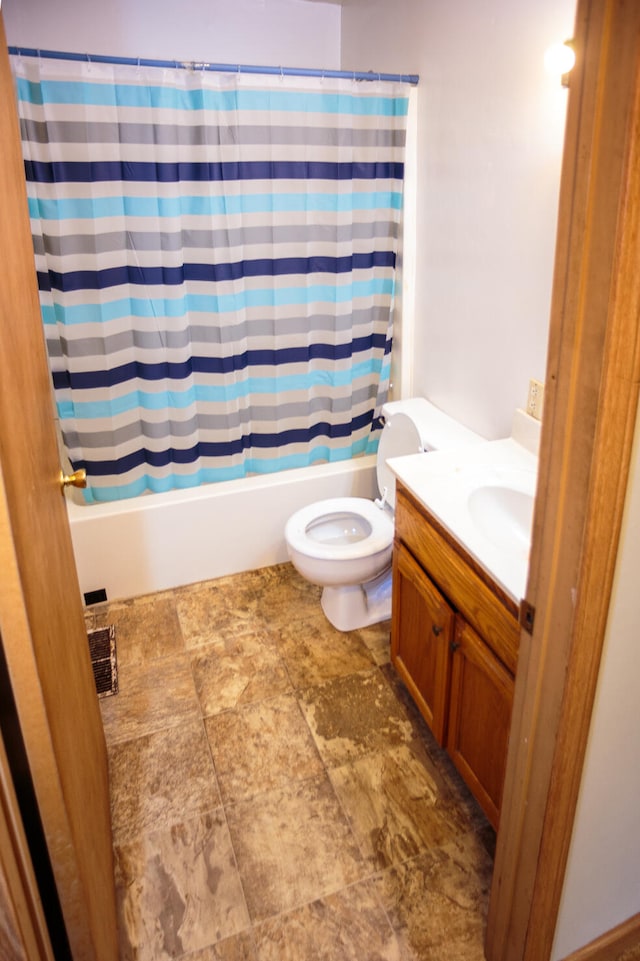 full bath with shower / bath combo with shower curtain, toilet, stone finish floor, and vanity