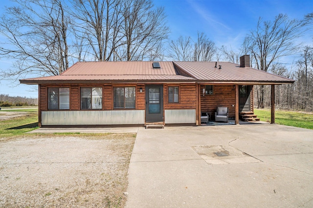 log-style house featuring a chimney and metal roof