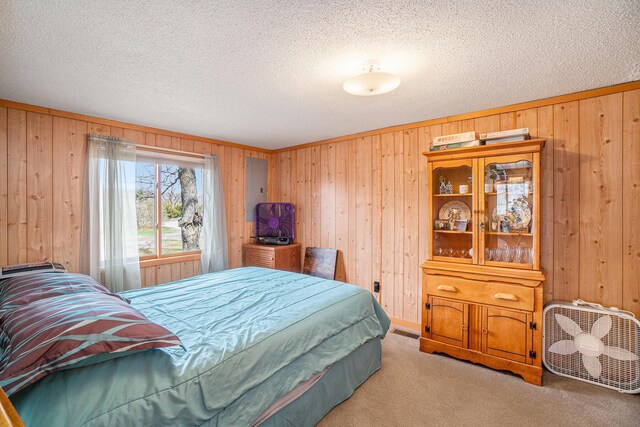 bedroom with a textured ceiling, carpet, and wooden walls