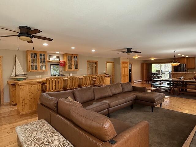 living room featuring bar, a baseboard radiator, a ceiling fan, and recessed lighting