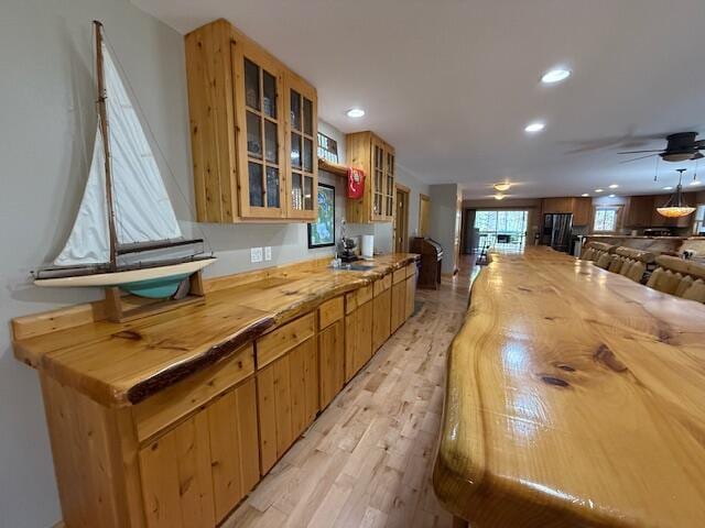 kitchen with glass insert cabinets, wood counters, recessed lighting, and light wood-style flooring
