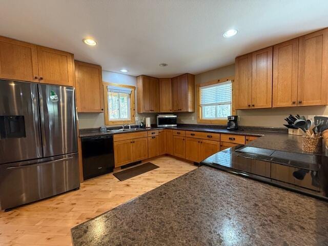 kitchen with a sink, dark countertops, stainless steel appliances, and a wealth of natural light