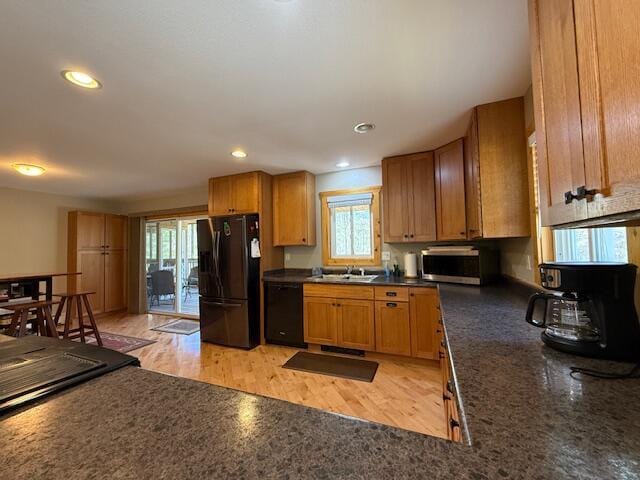 kitchen featuring a sink, brown cabinetry, recessed lighting, light wood-type flooring, and black appliances