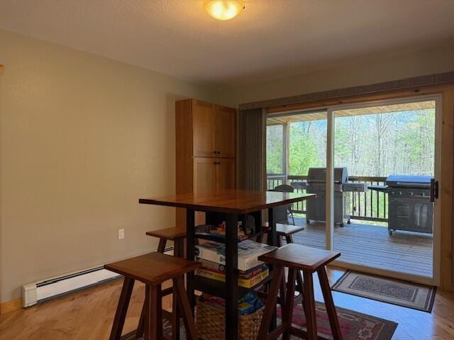 dining space with light wood-style floors, baseboards, and baseboard heating