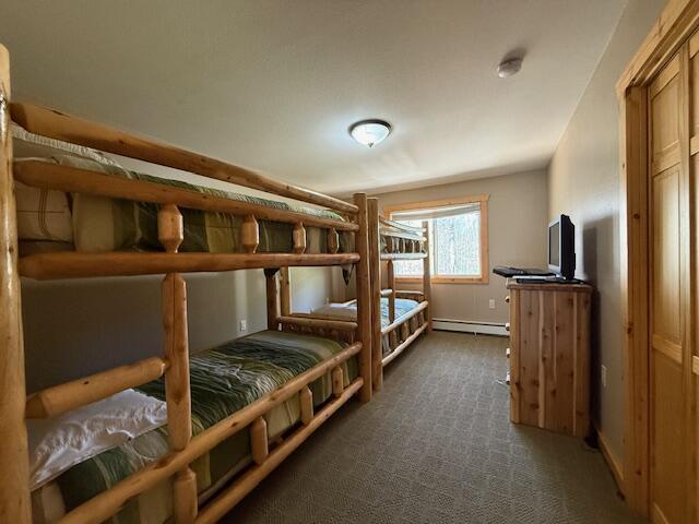 bedroom with dark carpet and a baseboard radiator