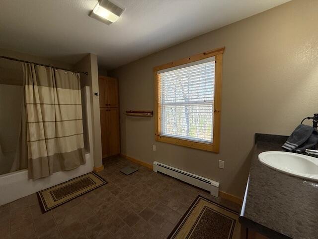 full bathroom featuring vanity, baseboards, baseboard heating, and shower / bath combo
