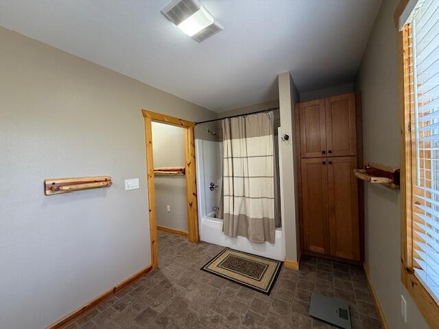full bathroom featuring baseboards, visible vents, shower / bath combination with curtain, and a wealth of natural light