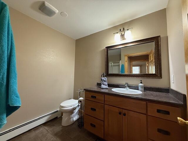 bathroom with visible vents, baseboard heating, vanity, tile patterned floors, and toilet