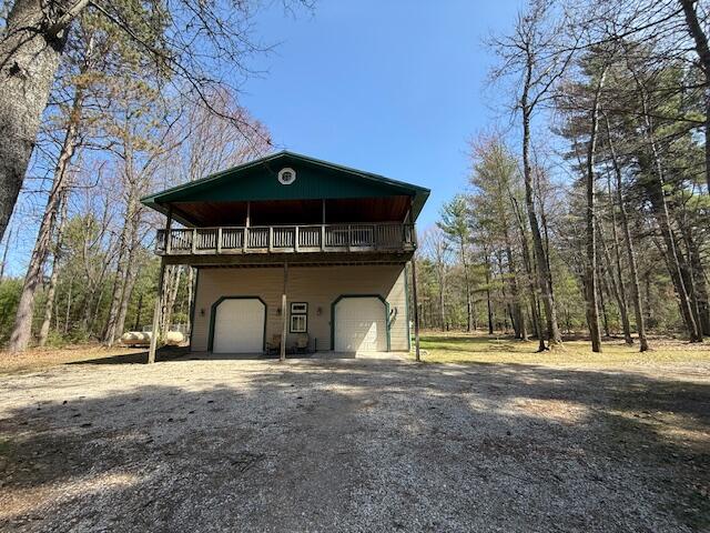 view of side of home with a wooden deck, an attached garage, and driveway
