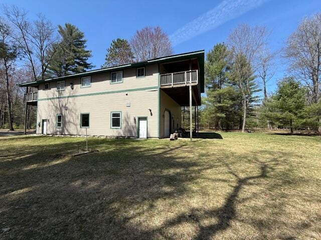 rear view of property featuring a balcony and a yard