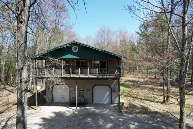 view of front of home featuring driveway, a wooden deck, and a garage