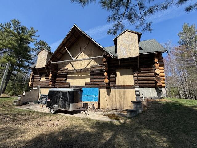 back of property with log siding and a chimney